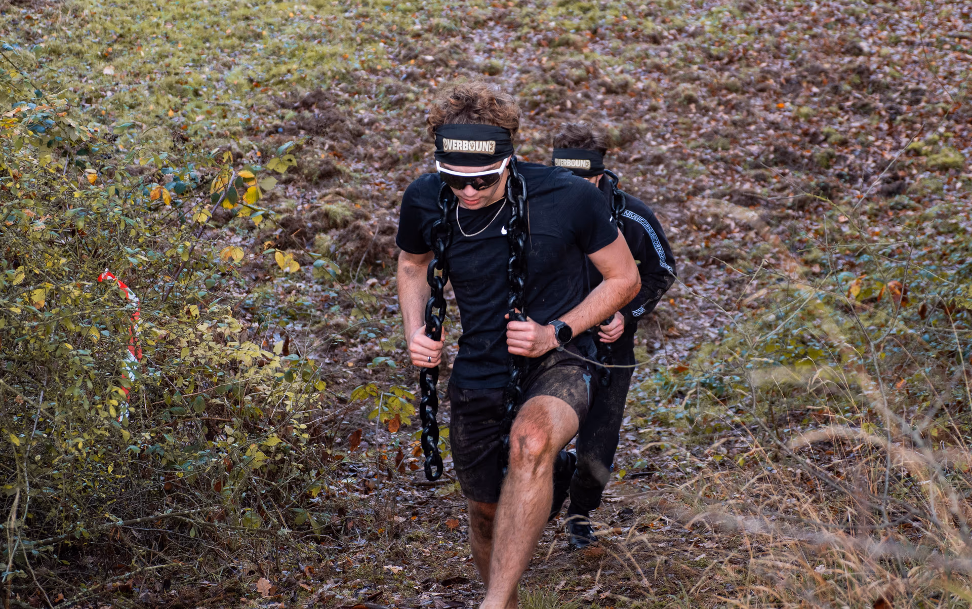 Deux coureurs montant une pente, chaînes sur le dos